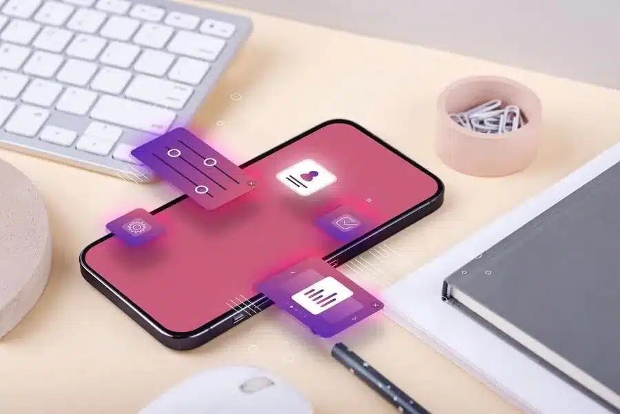 A imagem mostra um smartphone com diversos ícones e elementos gráficos, sugerindo uma interface de aplicativo ou plataforma digital. Nisso ilustra a importância do e-commerce omnichannel, pois uma plataforma integrada e com múltiplos recursos digitais pode oferecer uma experiência de compra e gestão mais eficiente e personalizada para os clientes, impactando positivamente a operação da empresa.