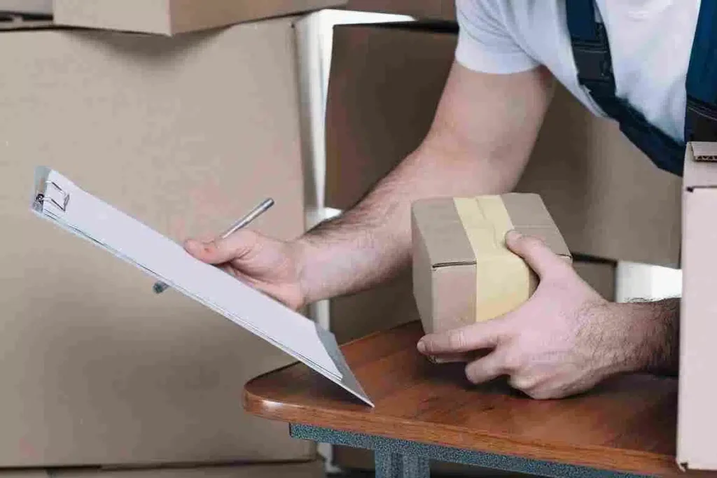Homem anotando informações em um caderno e empacotando um pacote, em um ambiente de armazém ou logística. Representa o processo de documentação e preparação de envios em operações de logística e distribuição.