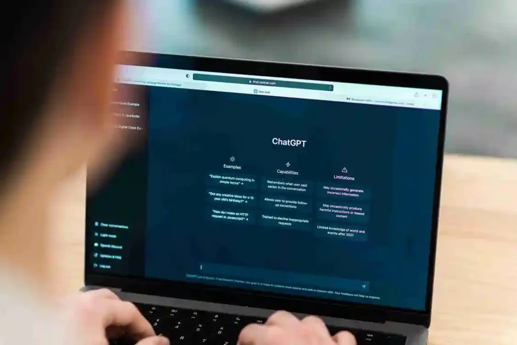 A imagem mostra uma pessoa usando um laptop com a página do ChatGPT aberta, ilustrando a utilização desse tipo de tecnologia em negócios.