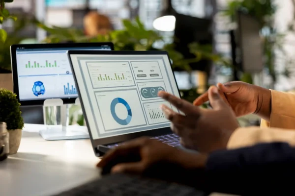Nesta imagem, profissionais de vendas online e e-commerce analisam dados em um laptop para otimizar suas estratégias de vendas e impulsionar o crescimento de negócios. A cena ilustra o uso de ferramentas de marketing digital para acompanhar as tendências de 2026 e tomar decisões informadas para a loja virtual. A imagem é um recurso visual ideal para artigos que discutem a importância da análise de dados e de um ERP robusto para o sucesso no mercado digital.